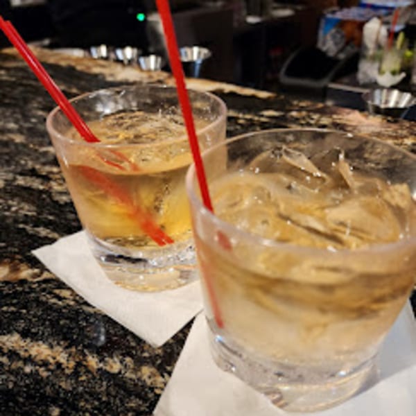 Two cocktails with ice and red straws on white napkins at Da Silva Steakhouse bar.